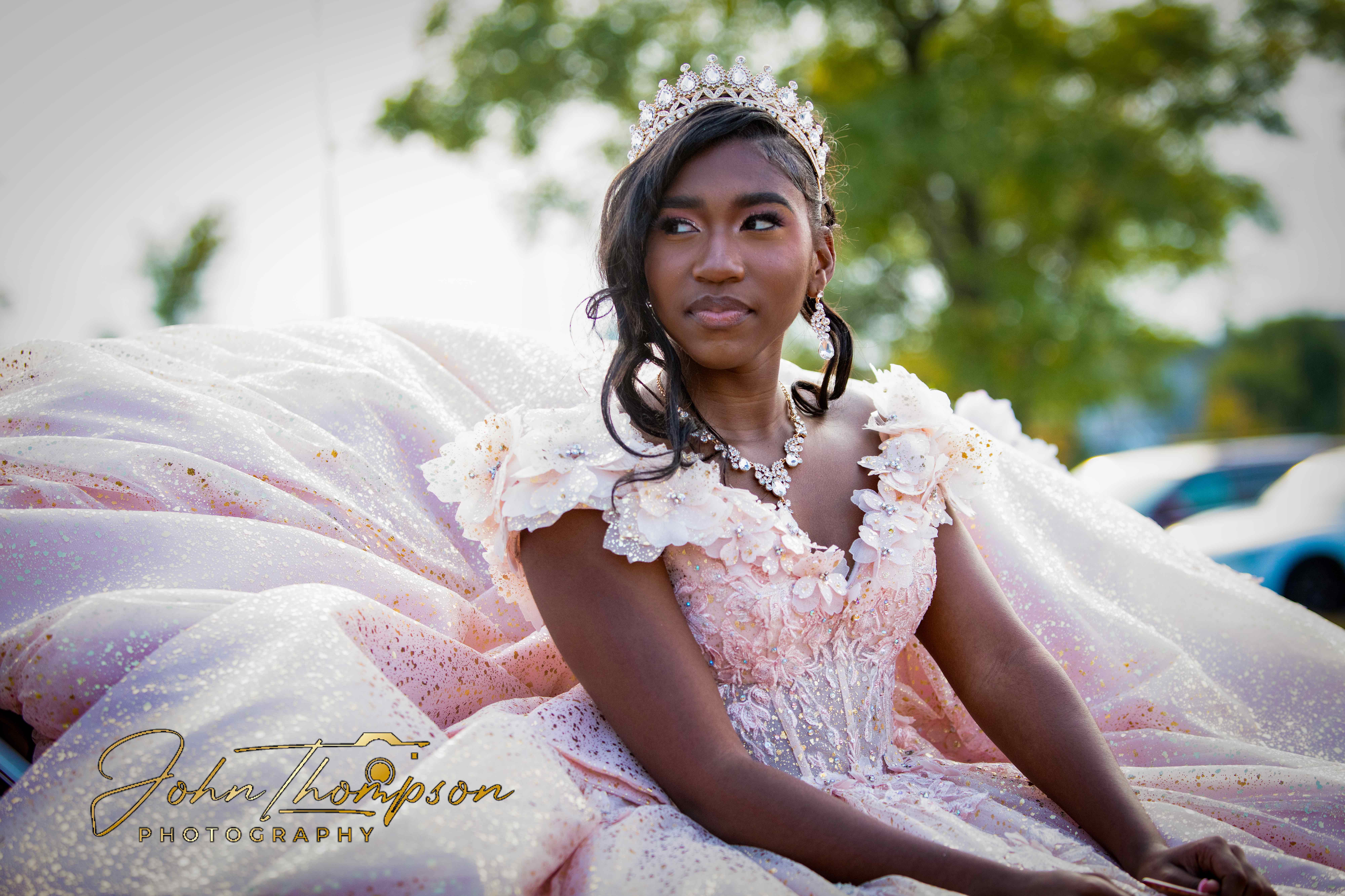 Young woman in a blush sequined ball gown and crystal tiara photographed outdoors at golden hour