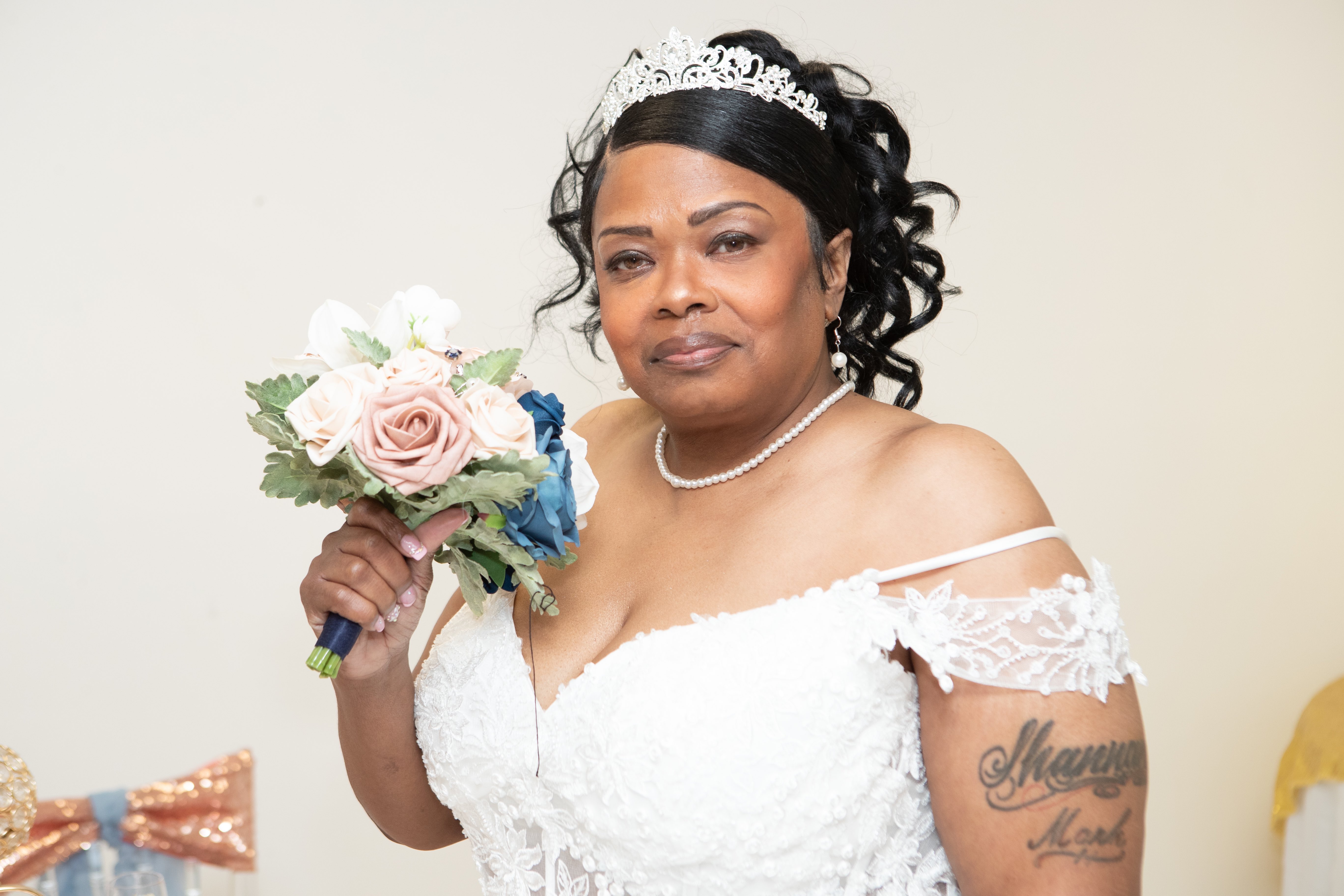 Bride in a tiara and lace gown holding a blush and navy rose bouquet